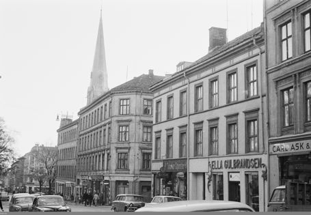 Sorthvitt-bilde av Grünerløkka, boligbygg nedover en gate med biler og mennesker, kirkespir i bakgrunnen