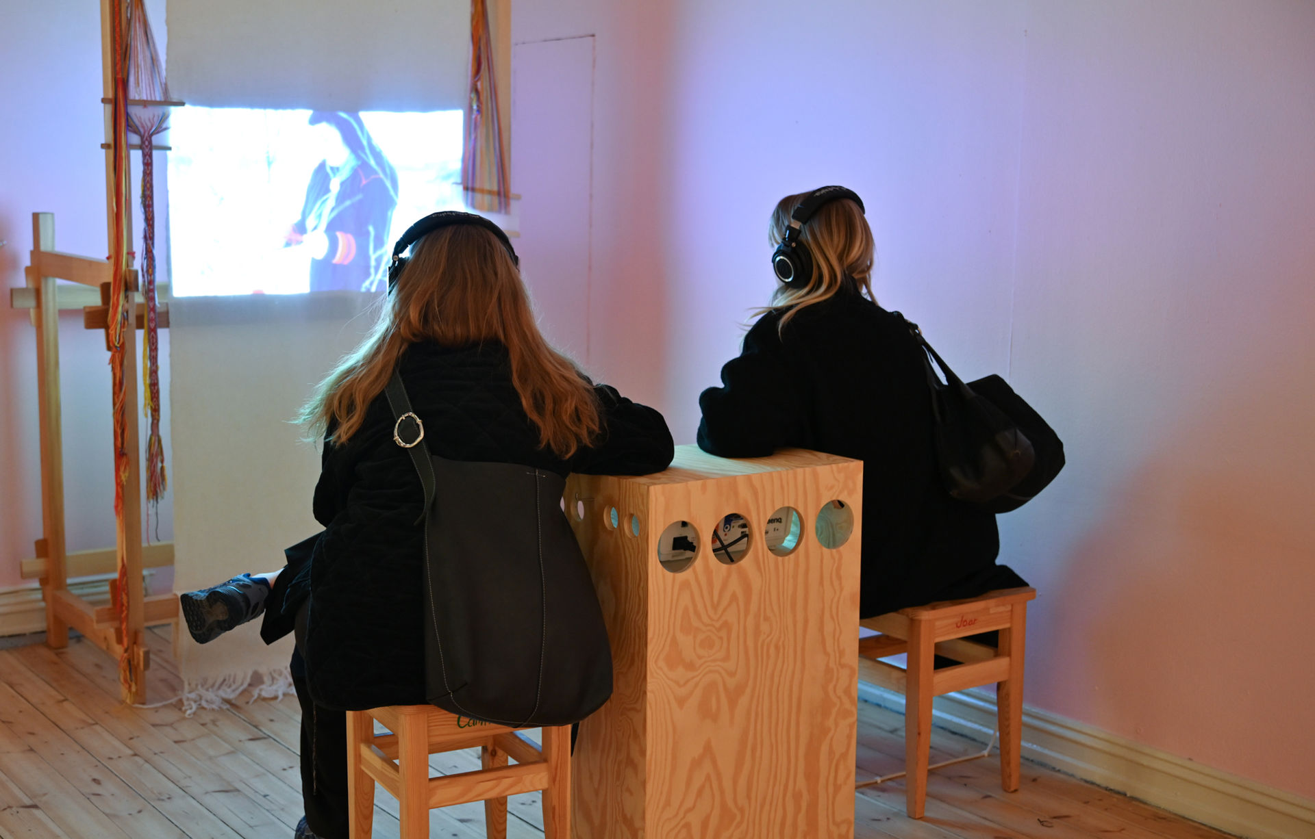 To damer sitter på hver sin krakk og ser på en film