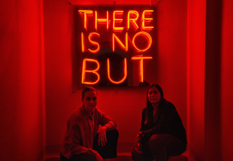 2 jenter foran neonskilt med teksten There is no but