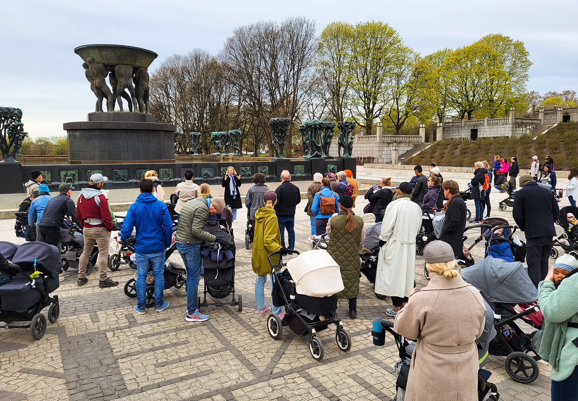 Mange mennesker med barnevogn på en åpen plass.