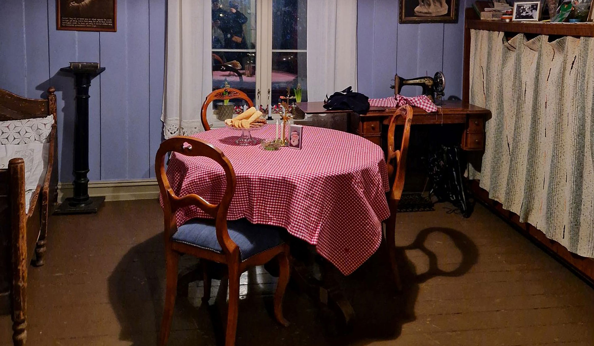 Tre gamle stoler rundt et bord med rødrutet duk.